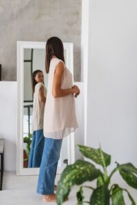 Woman looking at figure in the mirror | Feature image for Down With the Droop! How to Reduce Sagging Breasts | Blog