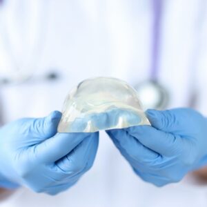 Photo of a cosmetic surgeon holding a breast implant | Featured image for are breast implants safe blog.