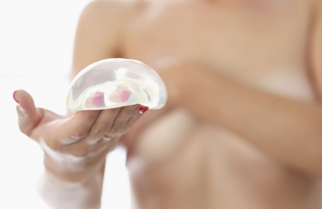 Lady holding a breast implant | Featured image for Benefits of Breast Reduction Surgery | Blog
